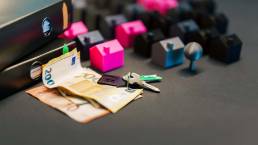 Case in miniatura, banconote in euro e chiavi di casa simboleggiano gli investimenti immobiliari e le transazioni immobiliari
